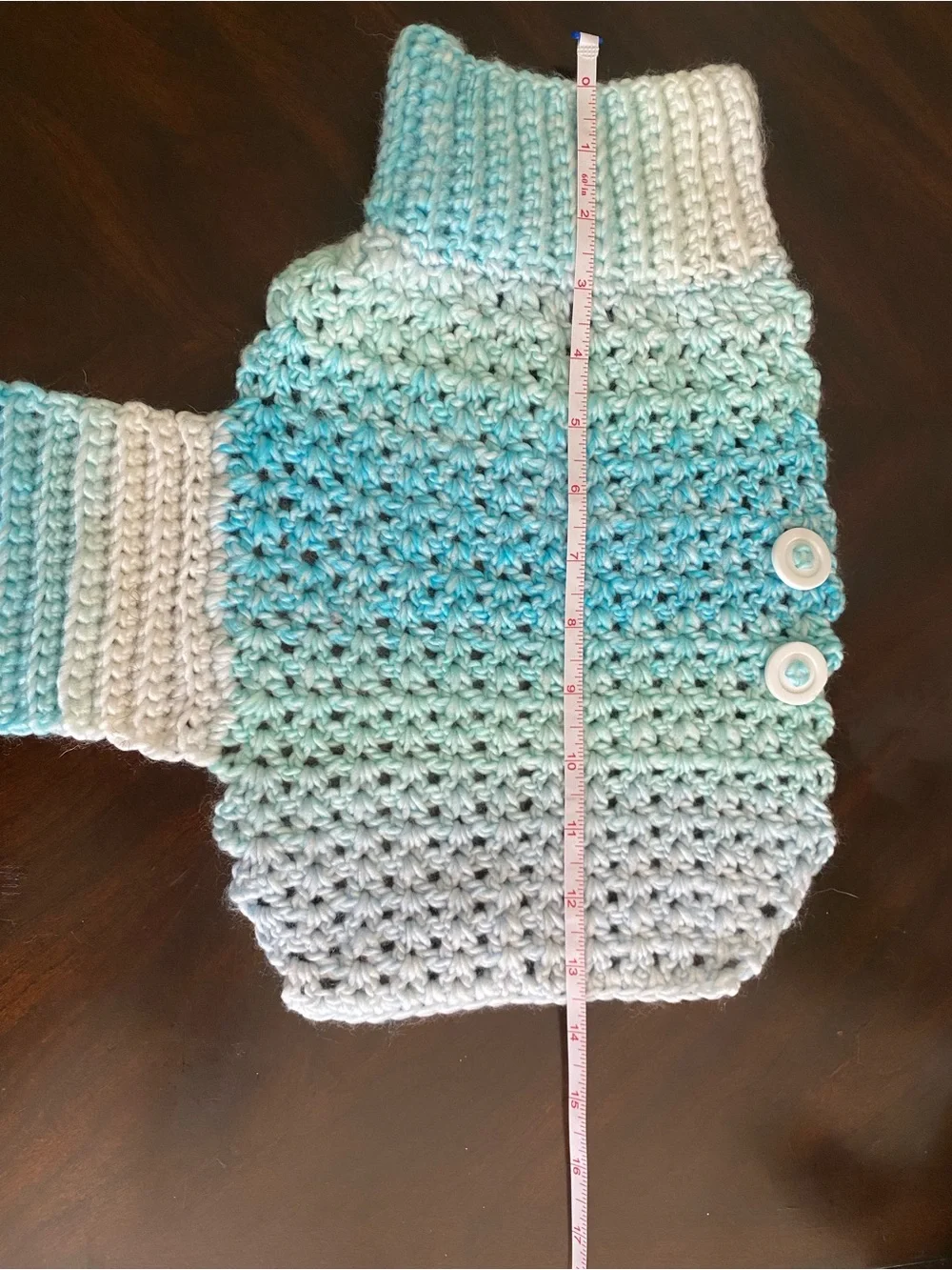 Hand-crocheted light blue dog sweater with buttons.